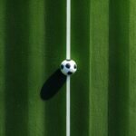 Góc nhìn flycam từ trên cao xuống quả bóng đá đặt giữa sân cỏ, minh họa bảng B ASEAN Cup 2026
